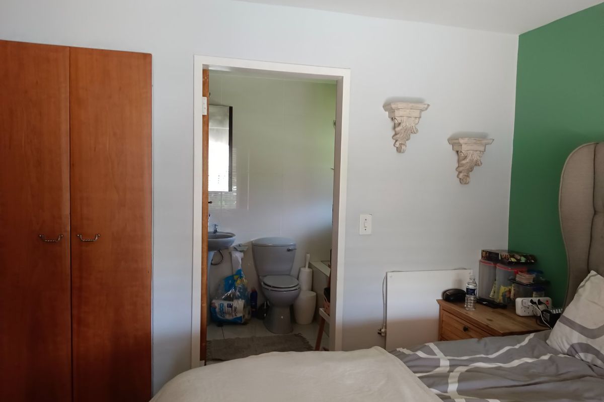 Bedroom featuring a built-in wooden wardrobe and direct access to an en-suite bathroom with tiled finishes.