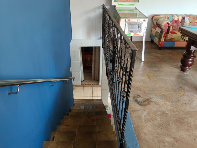 Staircase featuring a decorative wrought iron balustrade and stainless steel handrail, leading down to a lower level with tiled flooring.