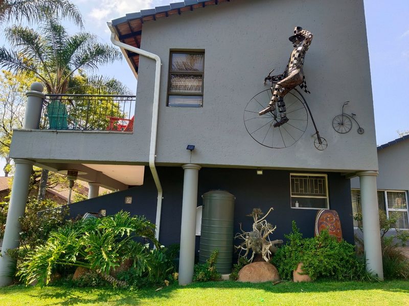 Rear elevation of the house featuring a raised balcony with wrought iron railings, concrete support columns, and a rainwater collection tank.