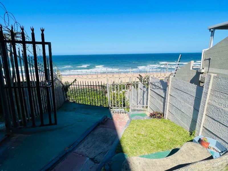 Rear outdoor area featuring a concrete boundary wall, security fencing with razor wire, and direct access to the beach.