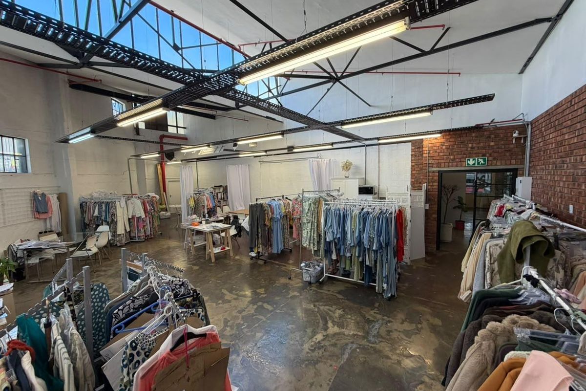 Spacious industrial-style open plan commercial unit featuring high ceilings with exposed steel trusses, polished concrete floors, and exposed brickwork accents.