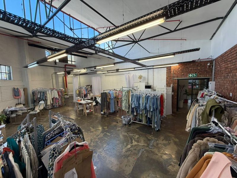 Spacious industrial-style open plan commercial unit featuring high ceilings with exposed steel trusses, polished concrete floors, and exposed brickwork accents.