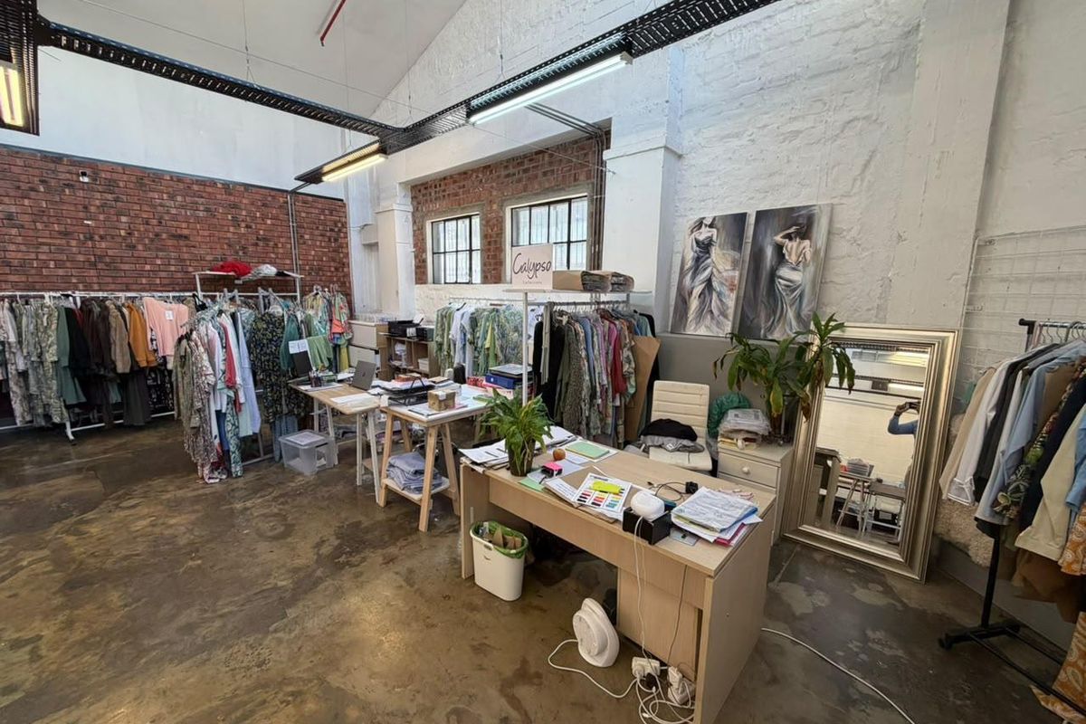 Spacious open-plan commercial unit featuring industrial aesthetics with exposed brick walls, high ceilings, cable trays, and polished concrete flooring.