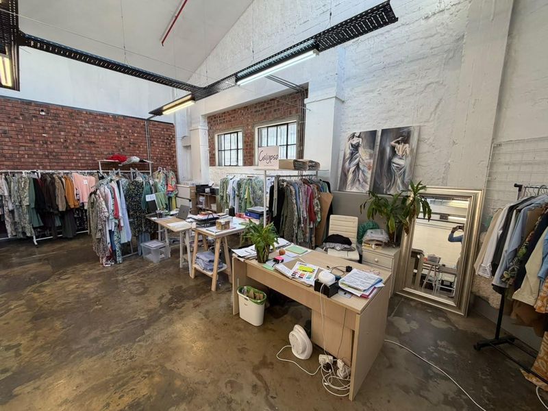 Spacious open-plan commercial unit featuring industrial aesthetics with exposed brick walls, high ceilings, cable trays, and polished concrete flooring.