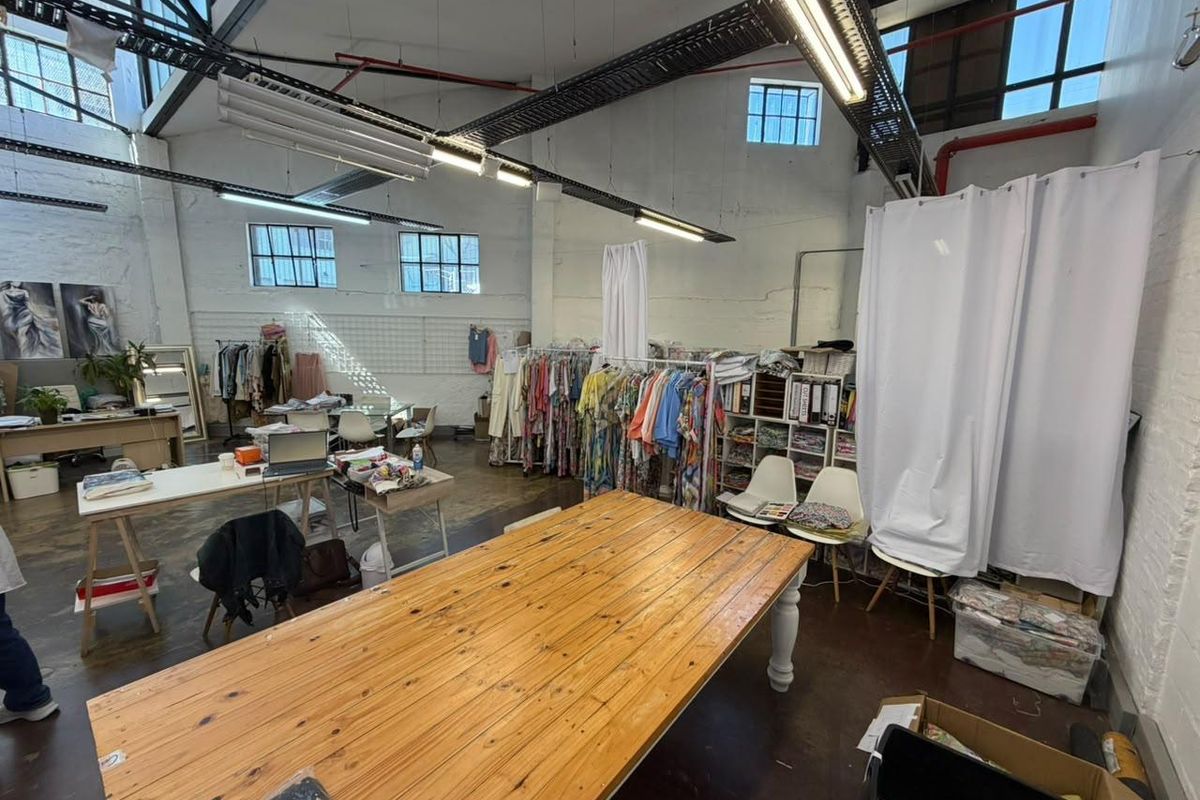 Spacious industrial-style open plan commercial studio featuring high ceilings with exposed trusses, large windows, and polished concrete floors, suitable for creative or retail use.