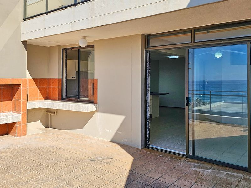 Spacious balcony featuring a built-in braai, tiled flooring, and sliding glass doors providing seamless access to the interior living area.
