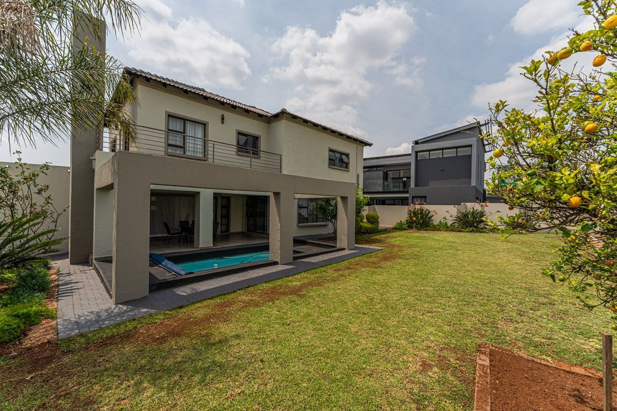 Rear view of the property featuring a covered patio, integrated swimming pool, balcony, and a well-maintained garden area.