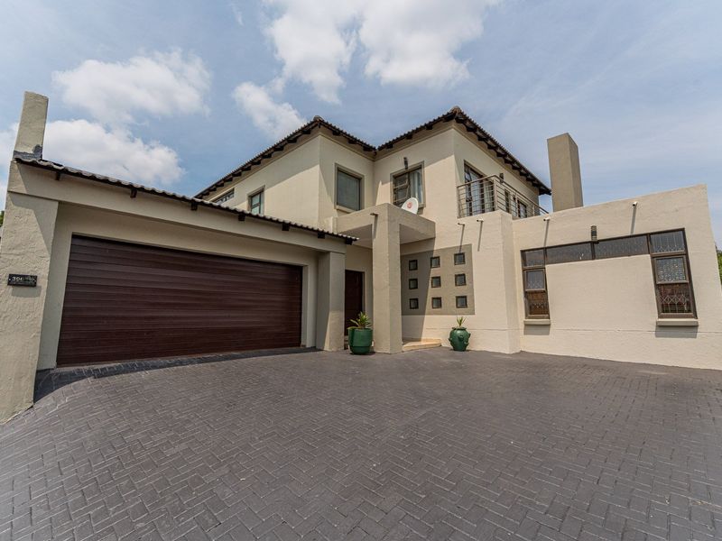 Front elevation of a modern double-story house featuring a paved driveway, double garage, and an upper-level balcony.
