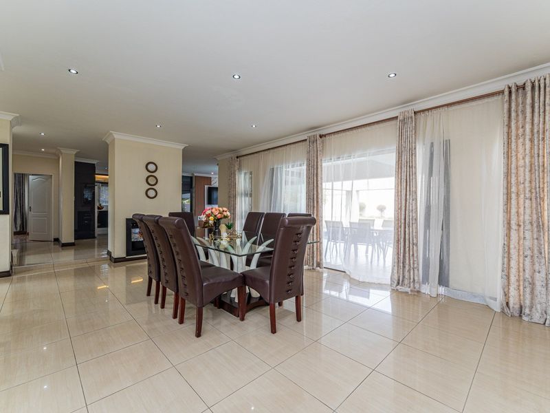 Spacious dining area featuring polished tile flooring, recessed downlighting, and large sliding glass doors providing seamless access to the outdoor patio.
