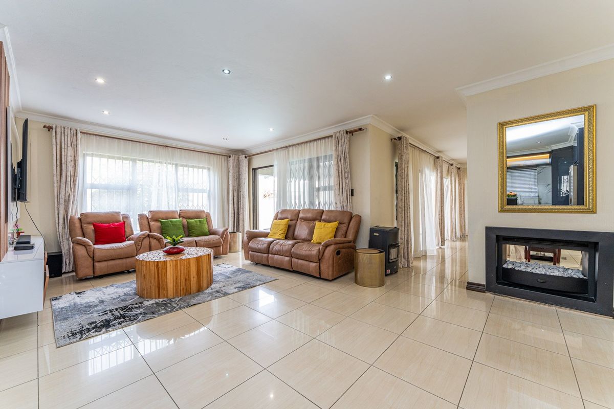 Spacious living room featuring large windows with security bars, tiled flooring, recessed lighting, and a modern built-in fireplace.