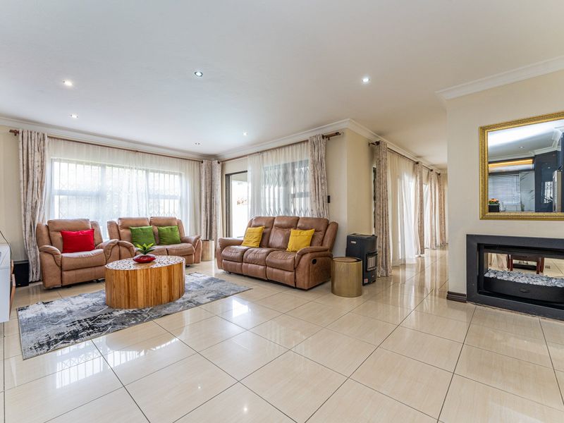 Spacious living room featuring large windows with security bars, tiled flooring, recessed lighting, and a modern built-in fireplace.