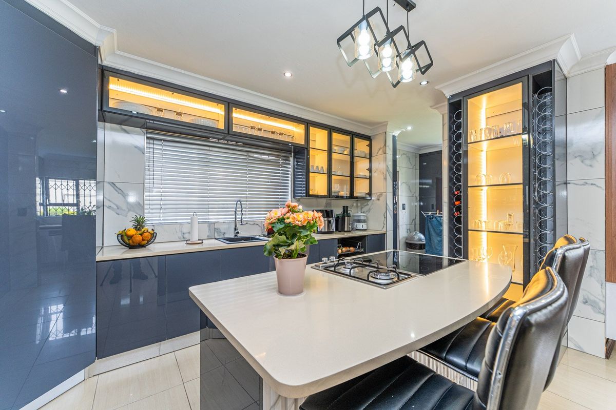 Modern kitchen featuring high-gloss cabinetry, stone countertops, integrated wine storage, gas hob, and elegant under-cabinet lighting with a sleek, contemporary finish.