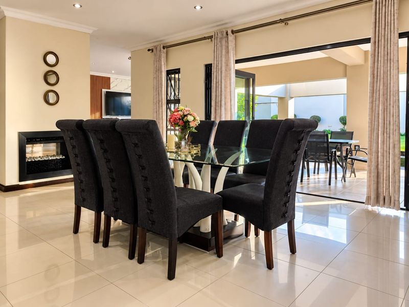 Elegant dining area featuring polished tiled floors, a modern built-in fireplace, and seamless flow to the outdoor patio through large sliding glass doors.