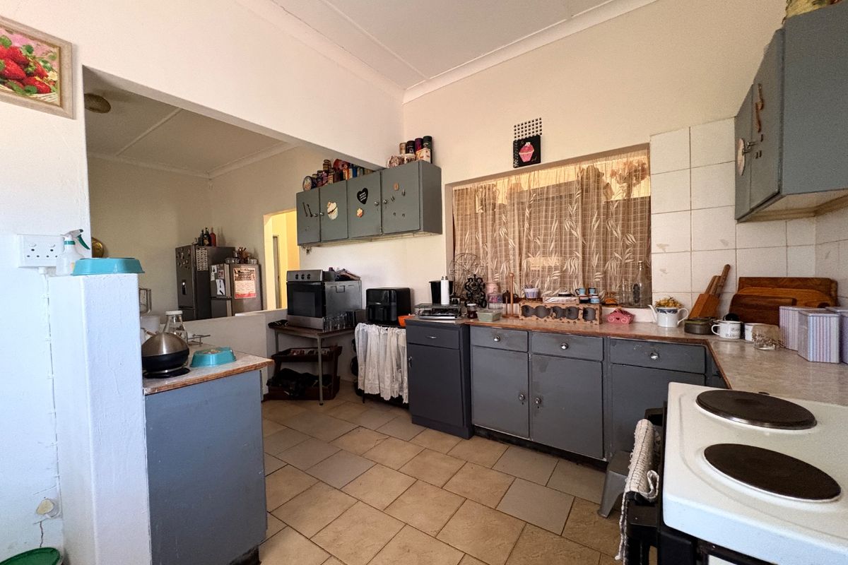 A dated kitchen featuring built-in cabinetry, tiled flooring, and a tiled backsplash, offering potential for modernization and renovation.