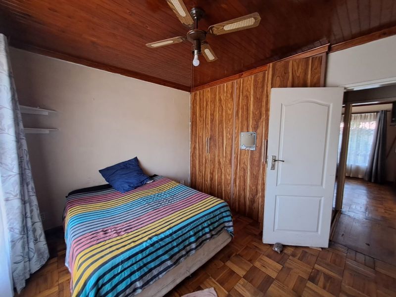 Bedroom featuring parquet flooring, a wooden ceiling with a fan, and built-in wooden cupboards.