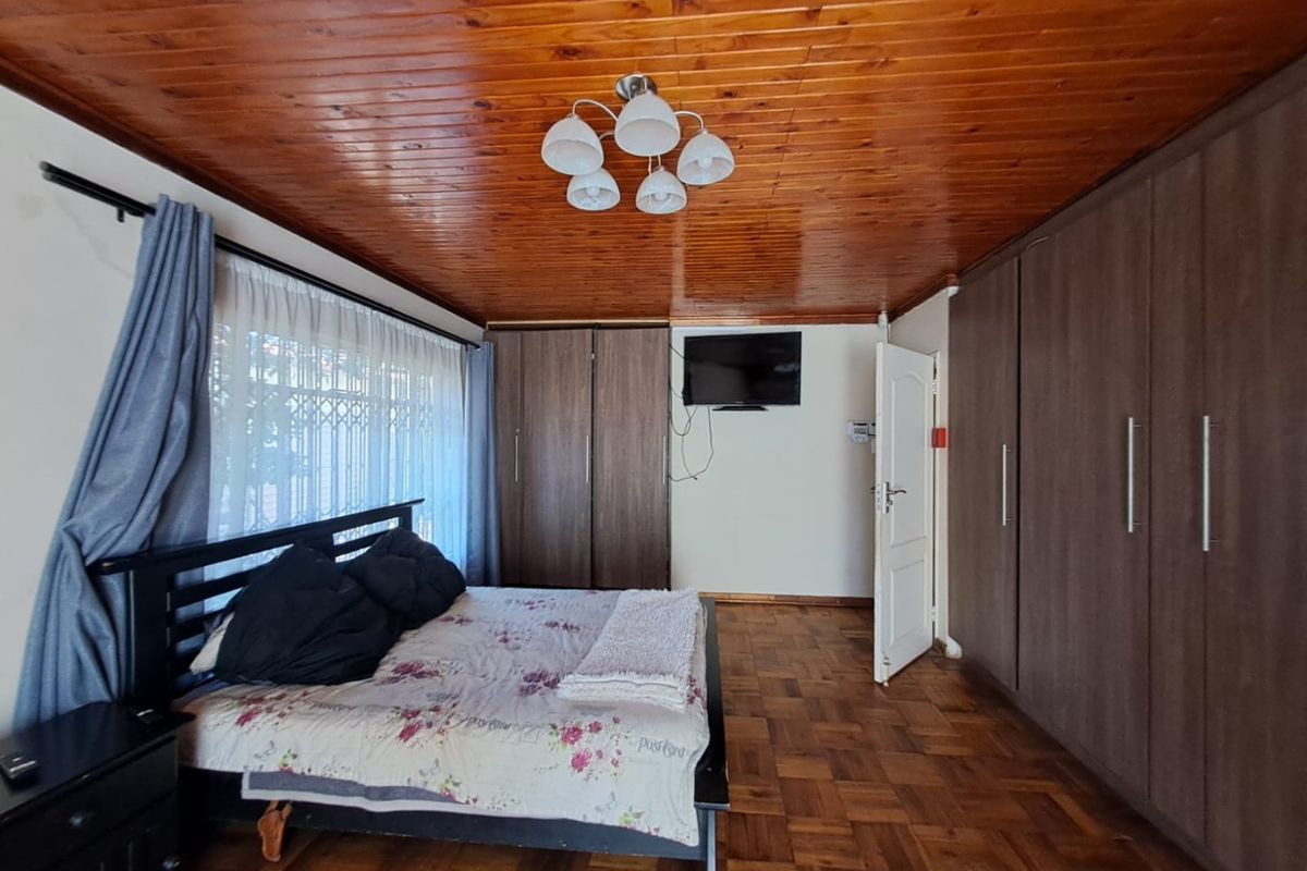 Spacious bedroom featuring warm timber ceiling, classic parquet flooring, and extensive built-in cupboard storage.