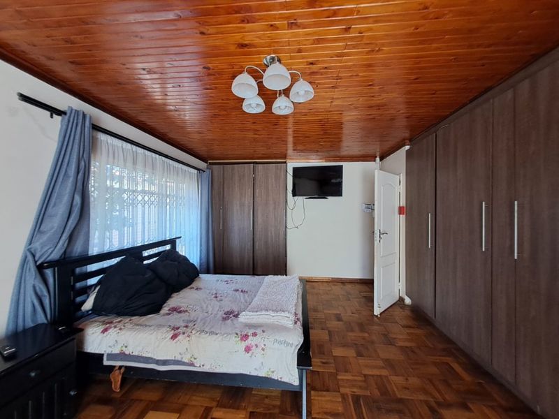 Spacious bedroom featuring warm timber ceiling, classic parquet flooring, and extensive built-in cupboard storage.