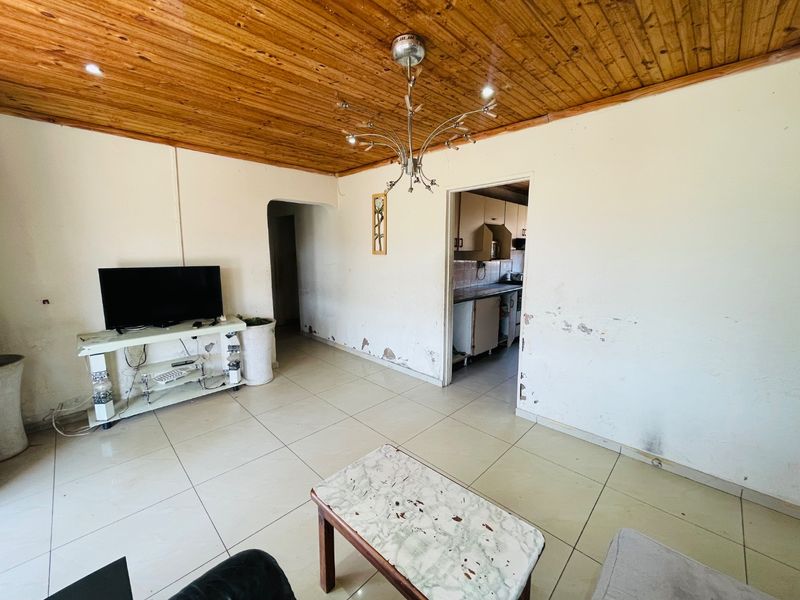 Living room featuring tiled flooring and a timber ceiling, requiring cosmetic wall repairs and updates to improve the overall aesthetic.