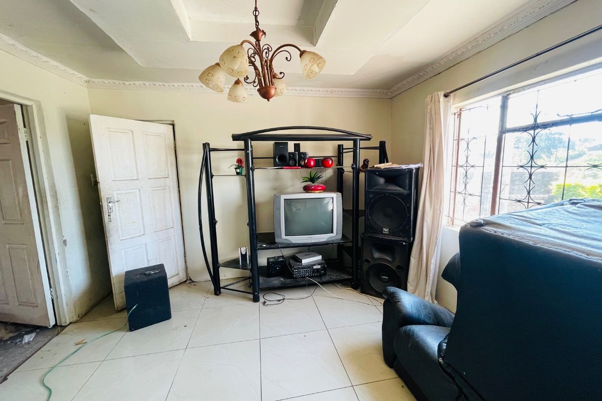 A living room featuring ceramic floor tiles, a tray ceiling with decorative cornice, and security bars on the windows.
