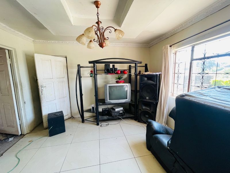 A living room featuring ceramic floor tiles, a tray ceiling with decorative cornice, and security bars on the windows.