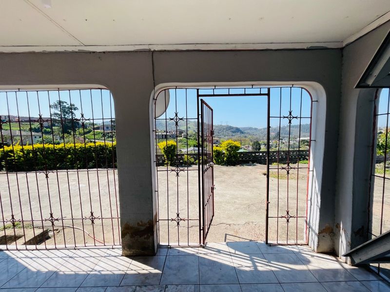 Covered patio area featuring tiled flooring and security gates, offering an open view of the surrounding landscape.