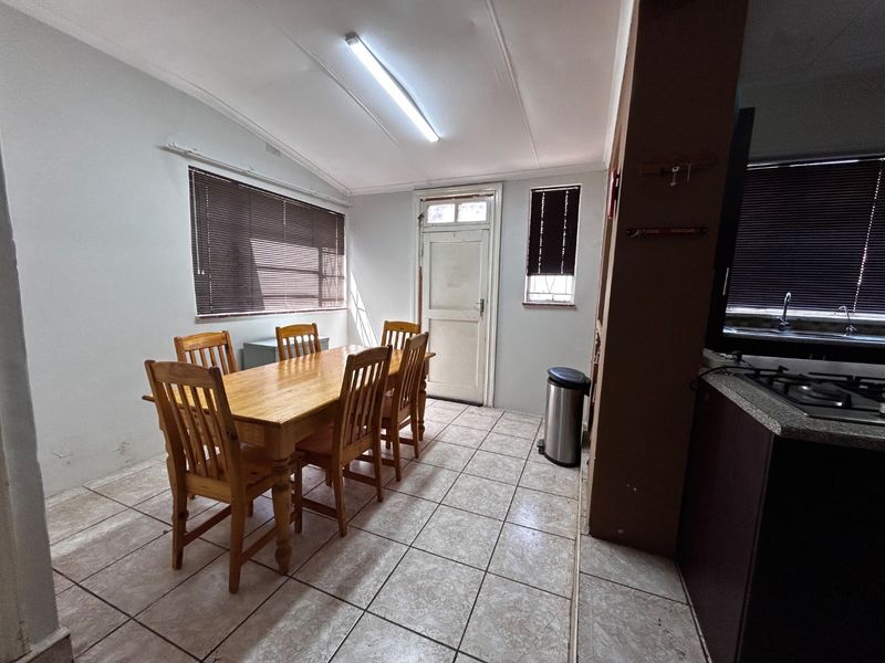 Open plan dining area adjacent to a kitchen featuring tiled floors, fluorescent lighting, and built-in cabinetry with granite countertops.