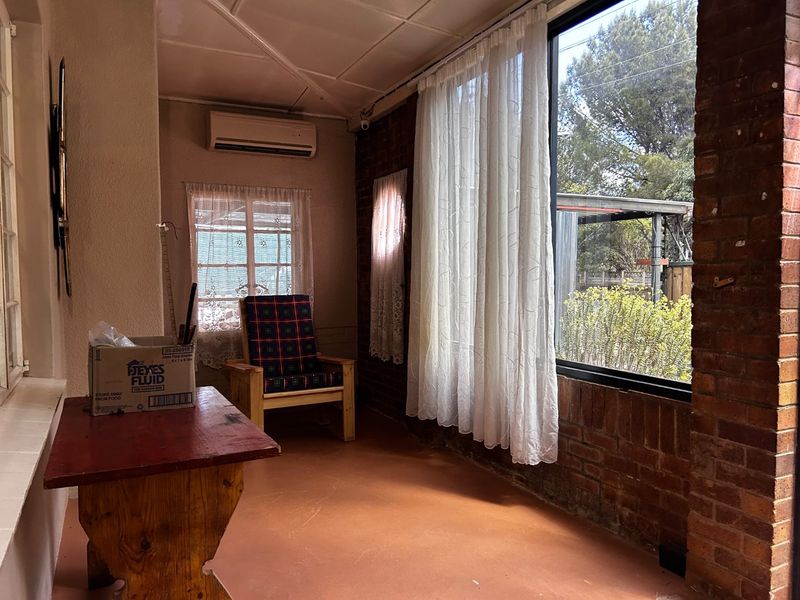 Enclosed patio area featuring exposed brick walls, large windows providing natural light, and a wall-mounted air conditioning unit.