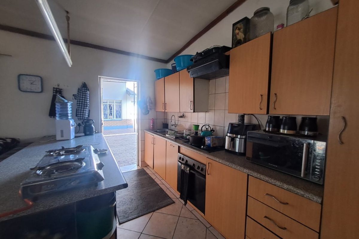 A functional kitchen featuring built-in cabinetry, a gas hob, and tiled flooring, with direct access to an outdoor area.