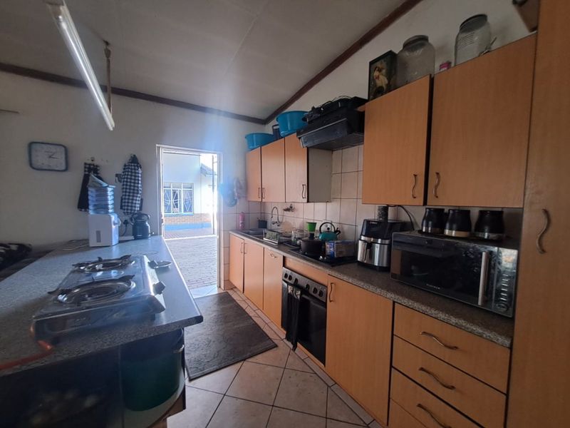 A functional kitchen featuring built-in cabinetry, a gas hob, and tiled flooring, with direct access to an outdoor area.