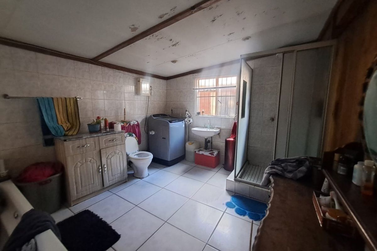 A functional bathroom featuring a shower enclosure, vanity cabinet, and basin, currently showing signs of ceiling wear and requiring cosmetic updates.