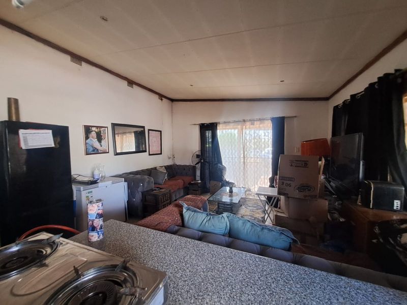 Open plan living area featuring a kitchen counter with a built-in gas hob and access to a patio through sliding glass doors.