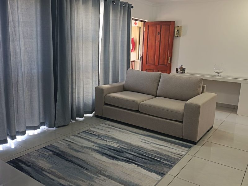 A living room area featuring tiled flooring, a timber entrance door, and an integrated intercom system.