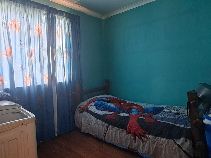 A bedroom featuring laminate flooring and coving, currently used as a multi-purpose space. The room requires cosmetic updates to improve its overall condition.