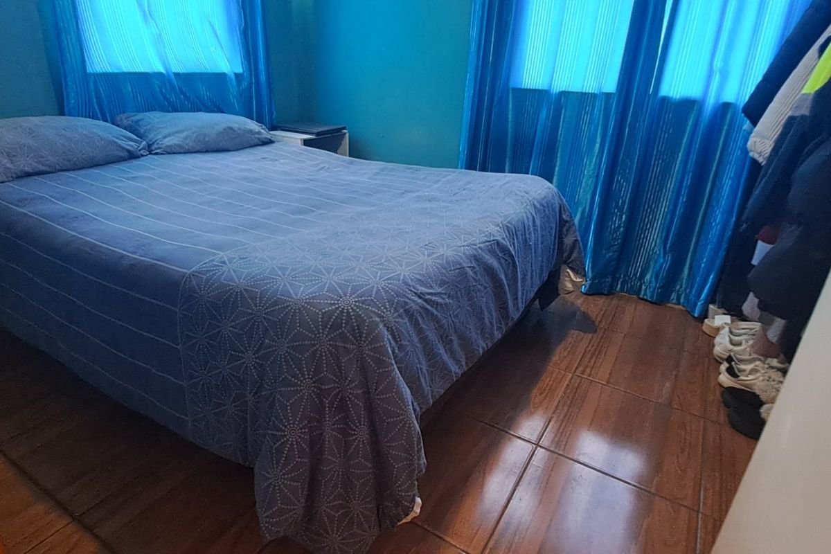 A bedroom featuring tiled flooring and blue curtains, providing a functional sleeping space.