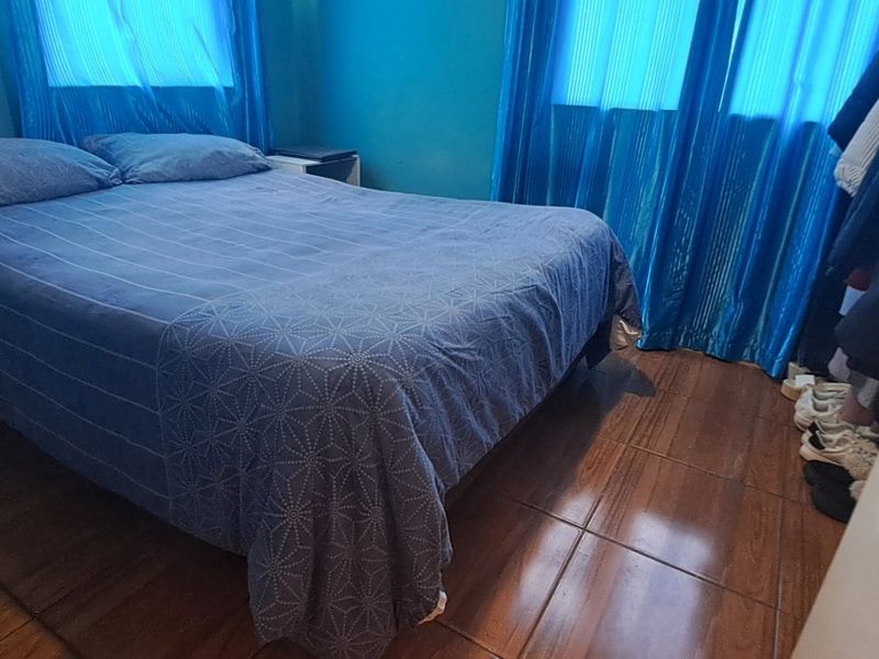 A bedroom featuring tiled flooring and blue curtains, providing a functional sleeping space.
