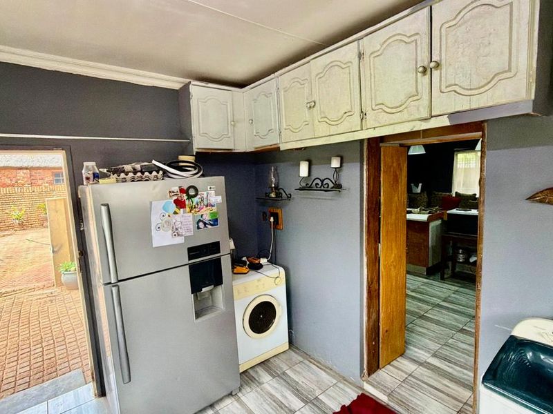 A functional laundry area featuring built-in cabinetry, tiled flooring, and direct access to the exterior patio.