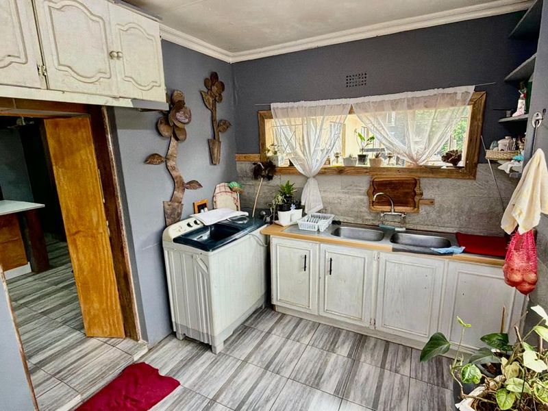 A functional laundry area featuring a double basin sink, built-in cabinetry, and tiled flooring, offering practical utility space for the home.