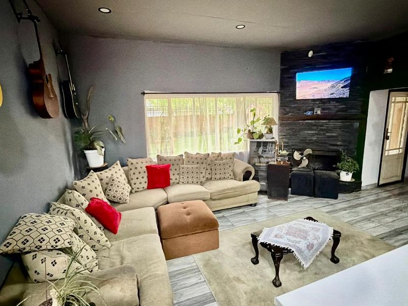 A comfortable living room featuring a stone-clad feature wall with an integrated fireplace, recessed downlighting, and modern tiled flooring.