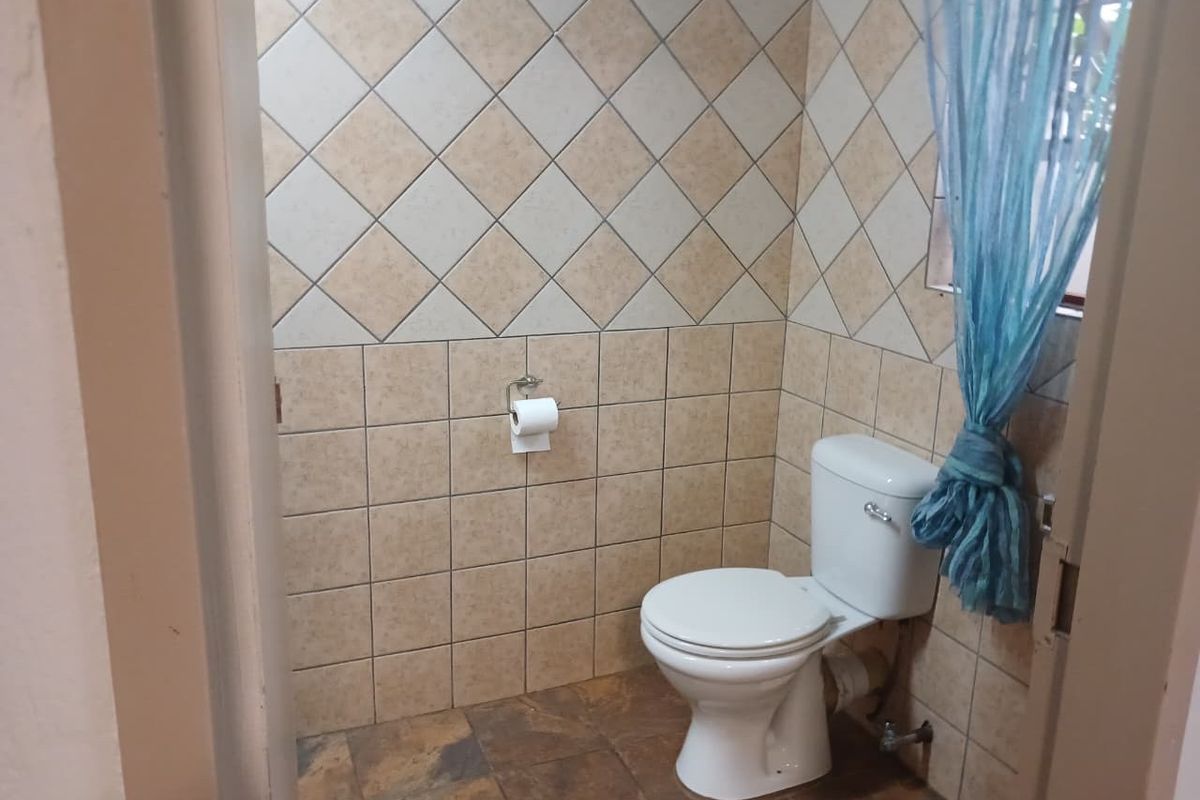 A functional bathroom featuring ceramic wall and floor tiling with a standard toilet suite.