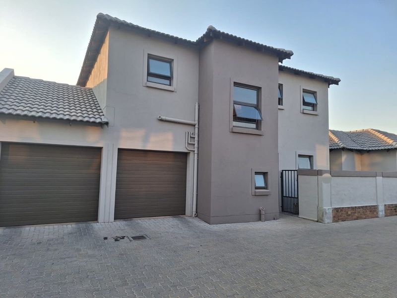 Front elevation of a modern double-storey house featuring a double garage, paved driveway, and neutral exterior paint finish.