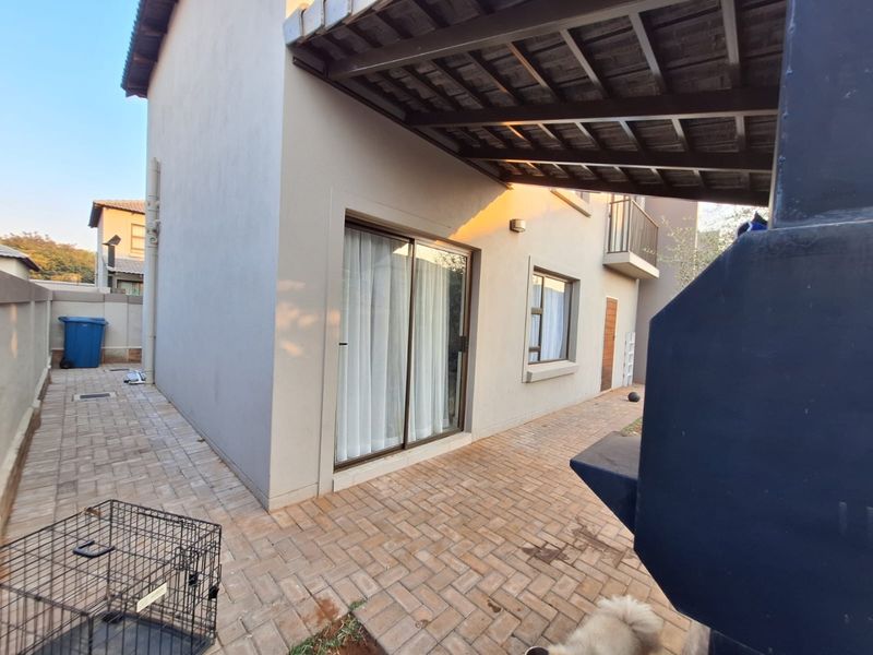 A covered outdoor patio area featuring paved flooring and a built-in braai, providing a functional space for outdoor entertaining.