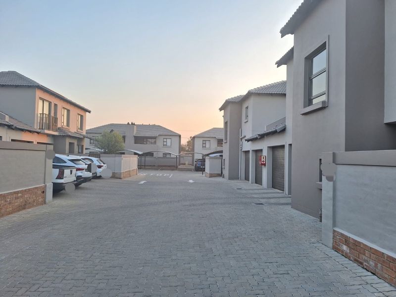 A view of the paved driveway and residential complex facade, featuring multiple garage doors and modern exterior finishes.
