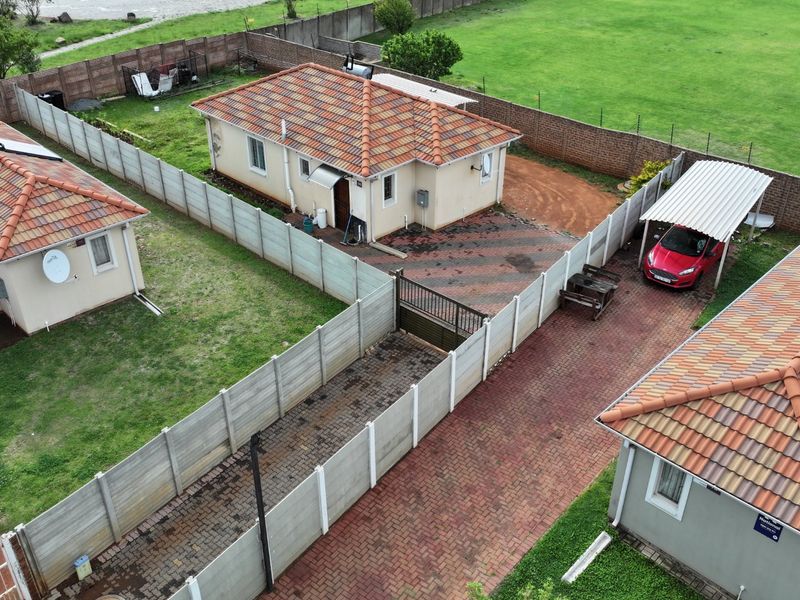 Aerial view of a residential property complex featuring multiple detached units with tiled roofs, paved driveways, and perimeter precast concrete walling.