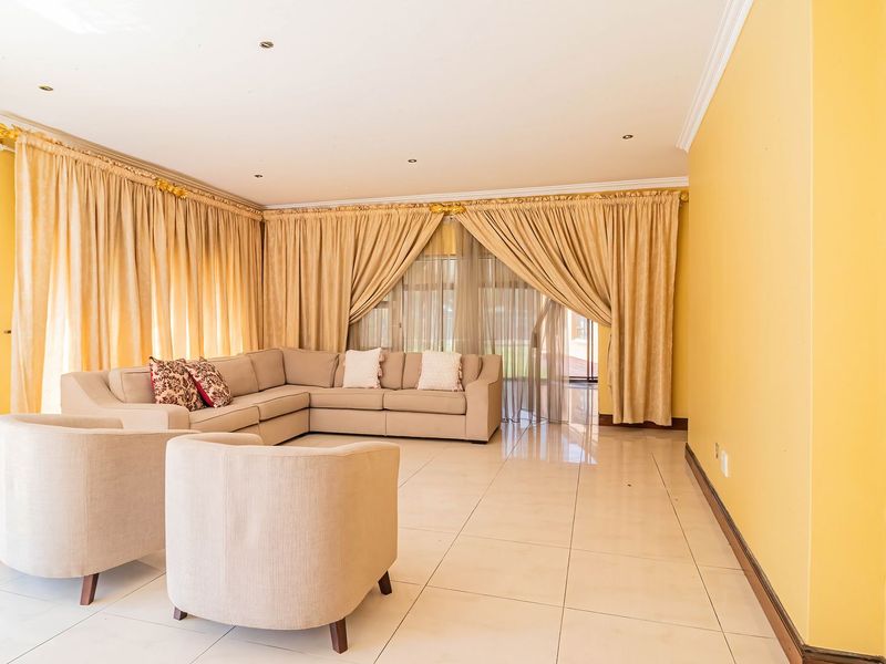 Spacious living room featuring large format floor tiles, recessed downlighting, and sliding glass doors leading to the exterior.