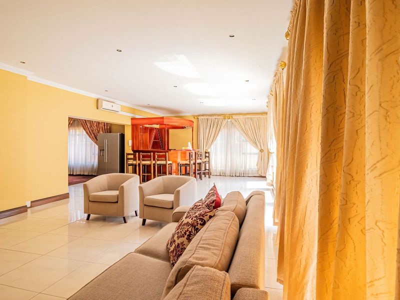 Spacious open-plan living area featuring tiled flooring, recessed lighting, a built-in bar, and a split-system air conditioner.