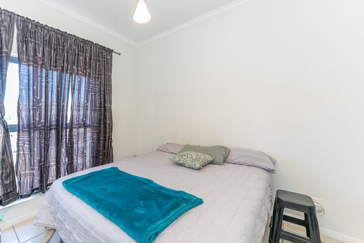 A functional bedroom featuring tiled flooring and simple cornice detailing, providing a neutral space ready for personalization.