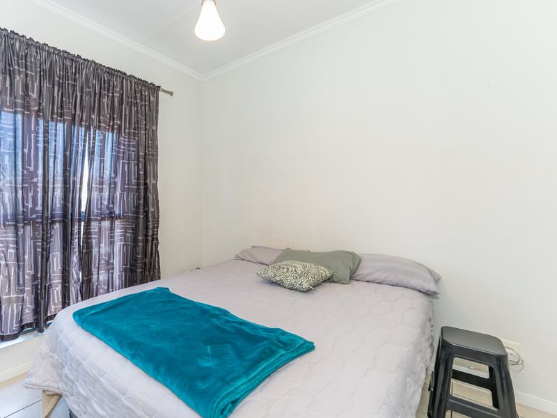 A functional bedroom featuring tiled flooring and simple cornice detailing, providing a neutral space ready for personalization.