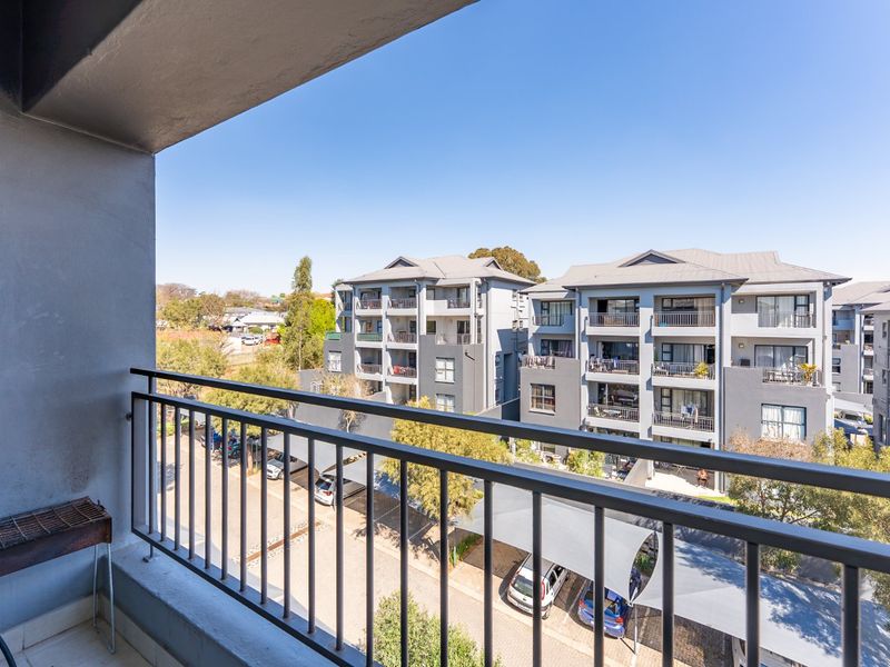 A private balcony featuring a metal balustrade, offering an elevated view of the surrounding residential complex and parking area.