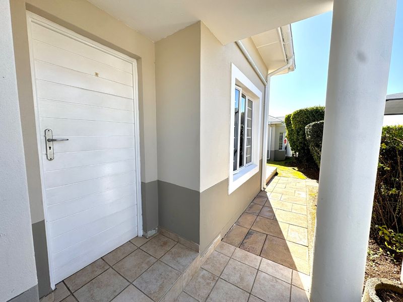 A clean and well-maintained entrance porch featuring tiled flooring, a structural column, and a white exterior door leading into the townhouse.