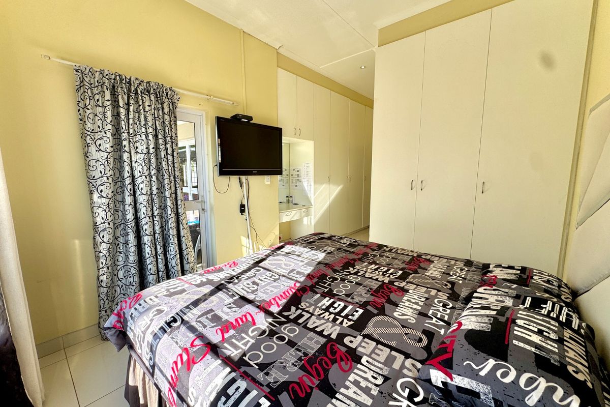 A bedroom featuring extensive built-in cupboards, tiled flooring, and a sliding door providing access to the exterior.